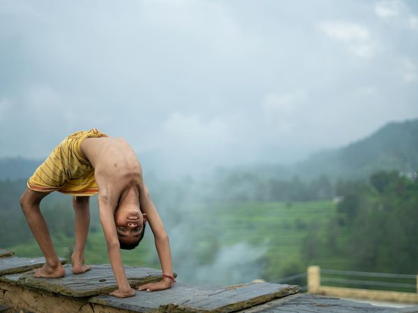 Person stretching peacefully outdoors with a serene landscape background.